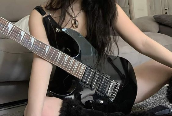 a woman sitting on the floor with a guitar in her lap and holding it up