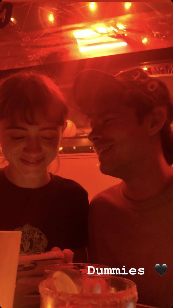 two people sitting next to each other in front of a table with food on it