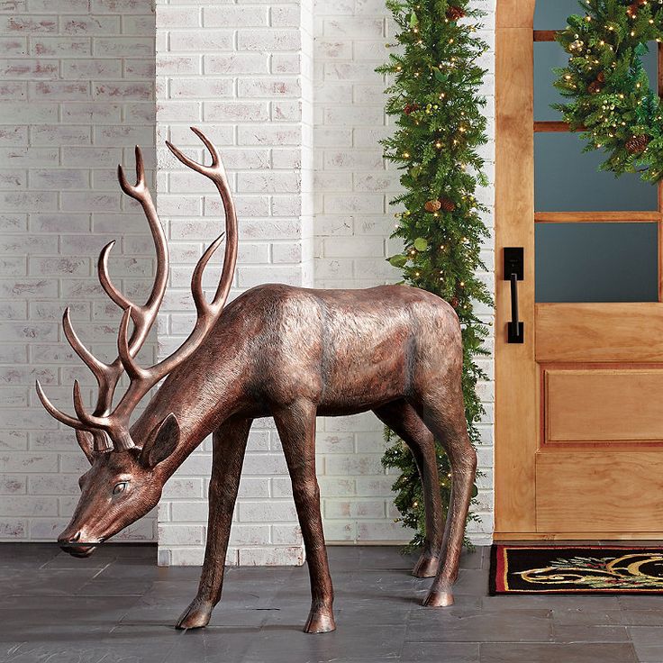 a statue of a deer eating grass in front of a door