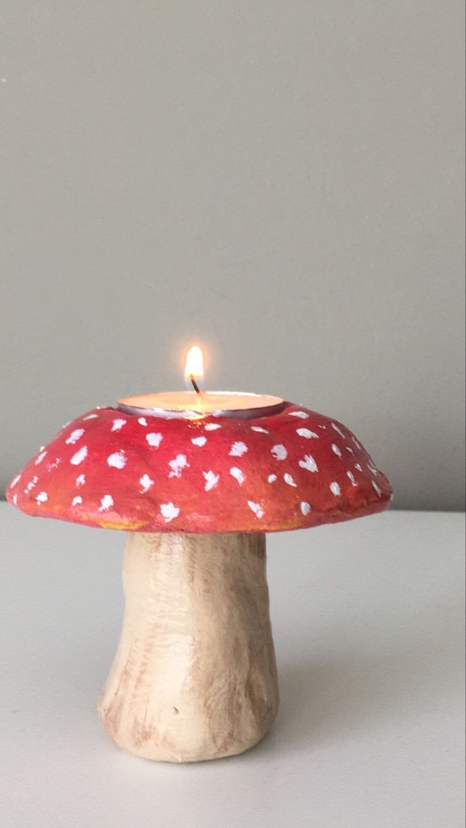 a small mushroom shaped candle holder with a lit candle in the middle on a white surface