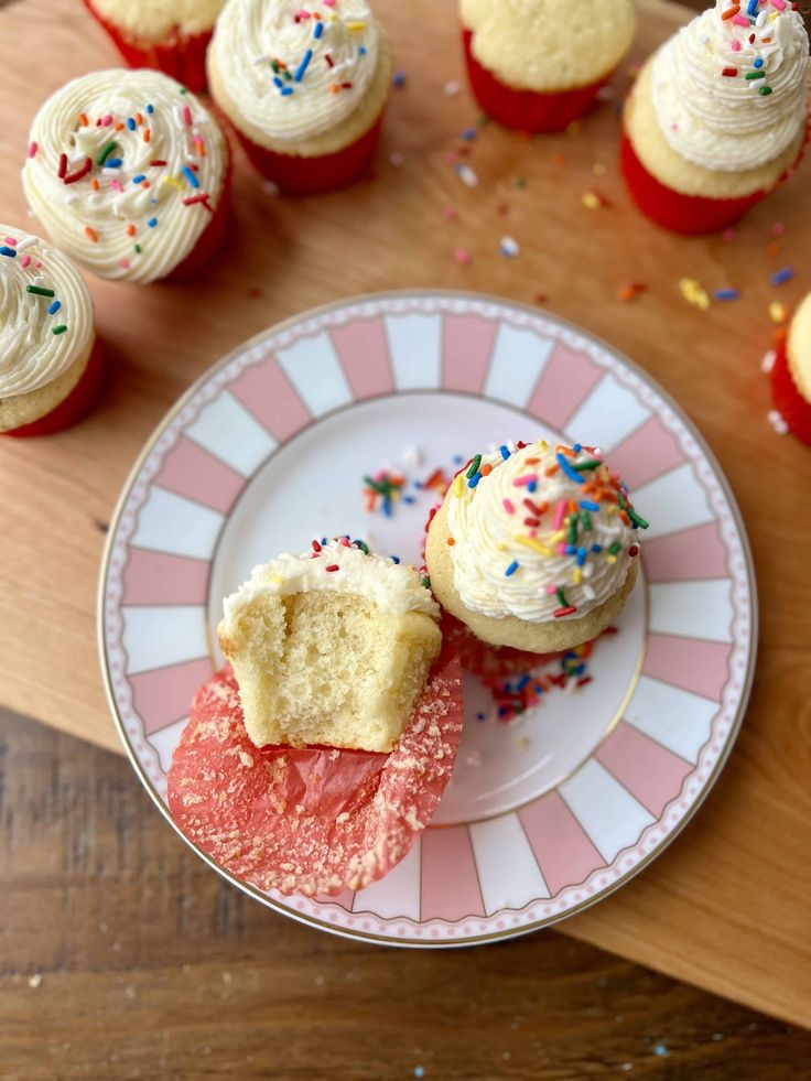 cupcakes with white frosting and sprinkles on a plate