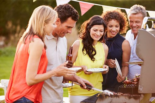 a group of people standing around a bbq grill