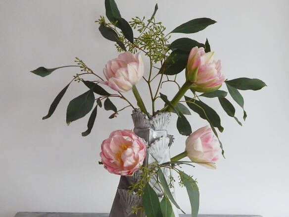 a vase filled with pink flowers sitting on top of a wooden table next to a white wall