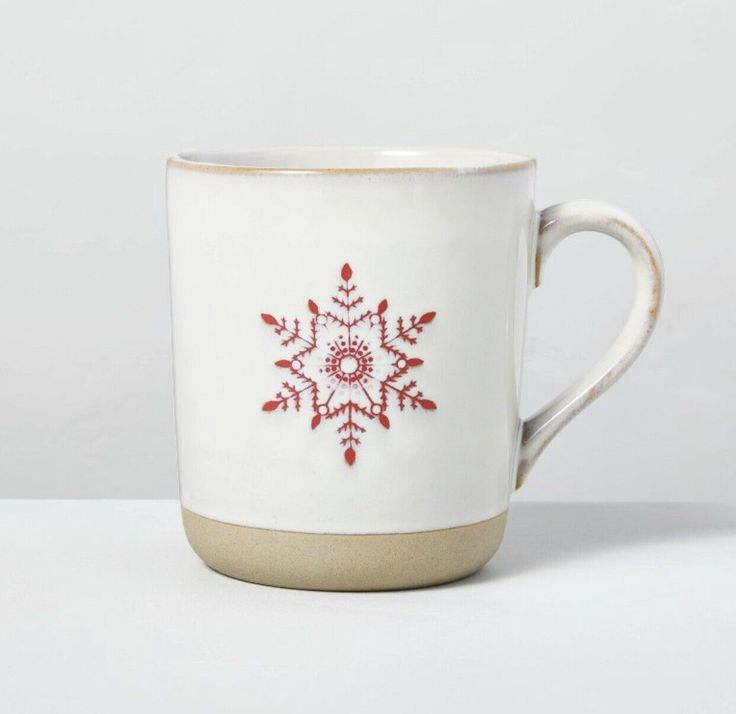 a white coffee cup with a red snowflake design on the inside and bottom