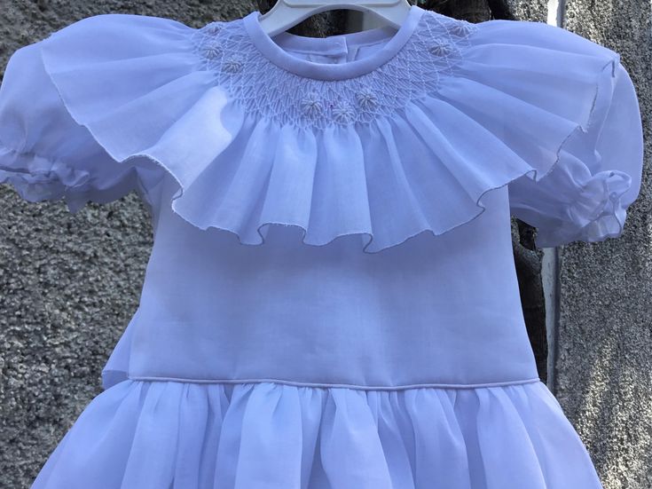 White smocked dress. Fully lined and ties on the back. Will be an appropriate dress for a flower girl, Christening or confirmation. Two are available SIZE 2T SIZE 6T For custom orders allow 2-3 weeks for delivery. Elegant Summer First Communion Dress, Elegant First Communion Dress For Summer Confirmation, Spring First Communion Dress With Ruffles, Spring First Communion Dress With Fitted Bodice, White Ruffled First Communion Dress For Spring, Elegant Fitted Baptism Dress With Smocked Bodice, First Communion Dress With Ruffles And Fitted Bodice, Summer Baptism Smocked Dress, Summer Baptism Dress With Smocked Back