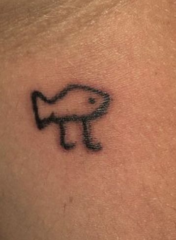 a small tattoo on the back of a woman's shoulder with an image of a fish