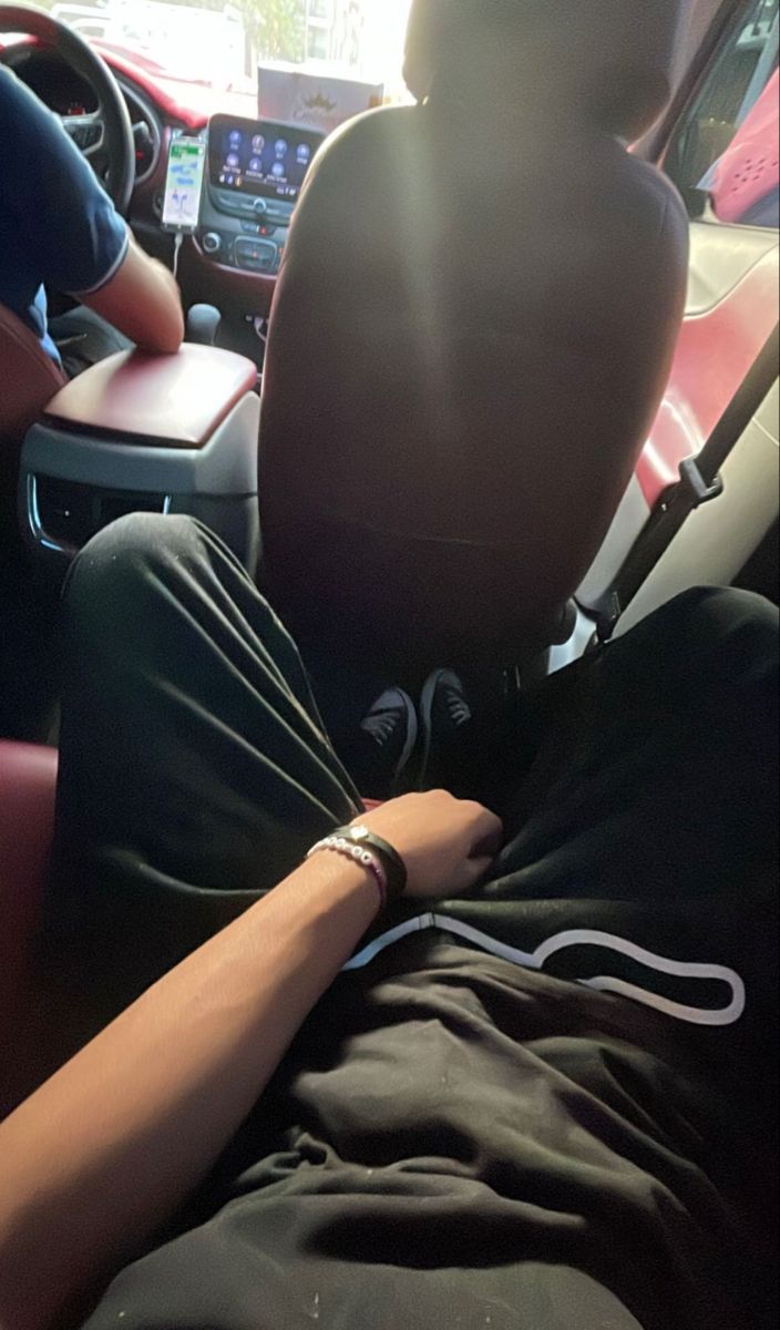 a person is sitting in the driver's seat of a car with their hands on his lap