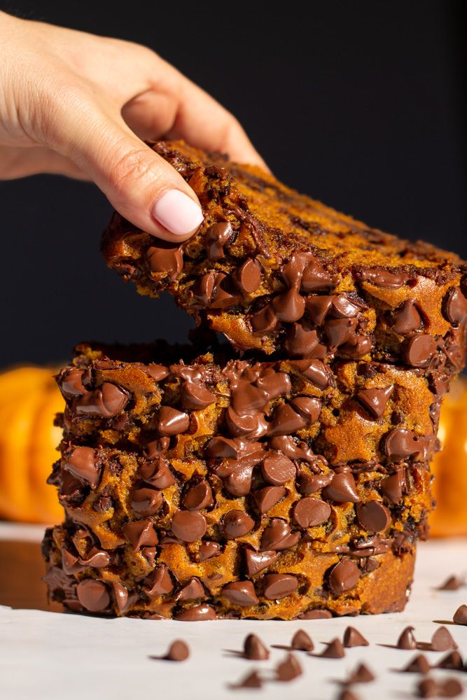 a person is picking up some chocolate chip pumpkin bread from the stack on top of each other