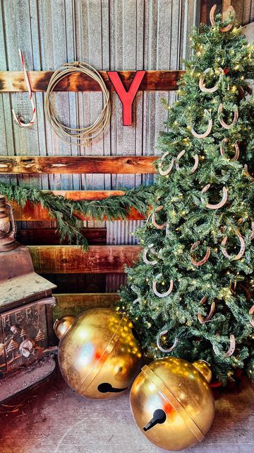 a christmas tree and two gold ornaments in front of a wall with the word joy on it