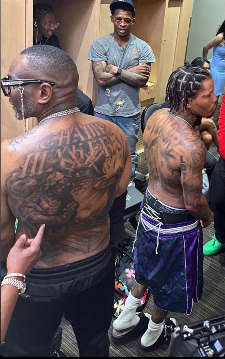 two men with tattoos on their back standing next to each other in a locker room