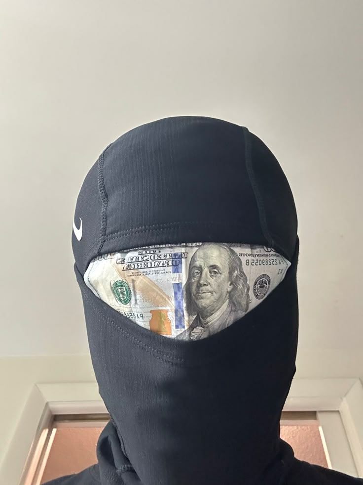 a person wearing a black mask with money sticking out of it