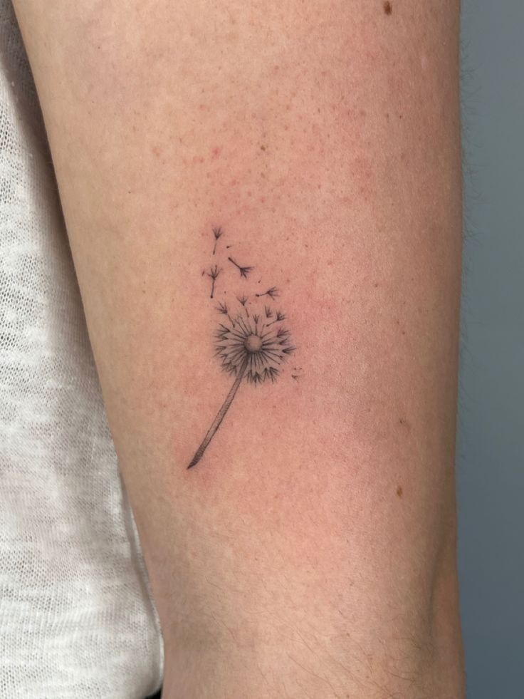 a small dandelion tattoo on the arm