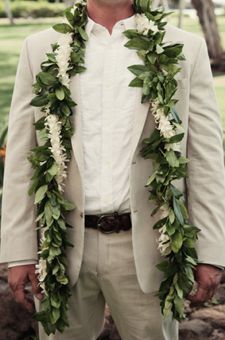 a man wearing a white suit and flower lei