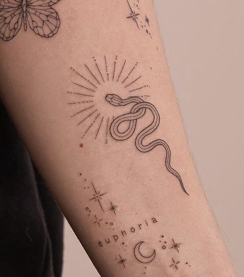 a woman's arm with a tattoo on it that has a snake and stars