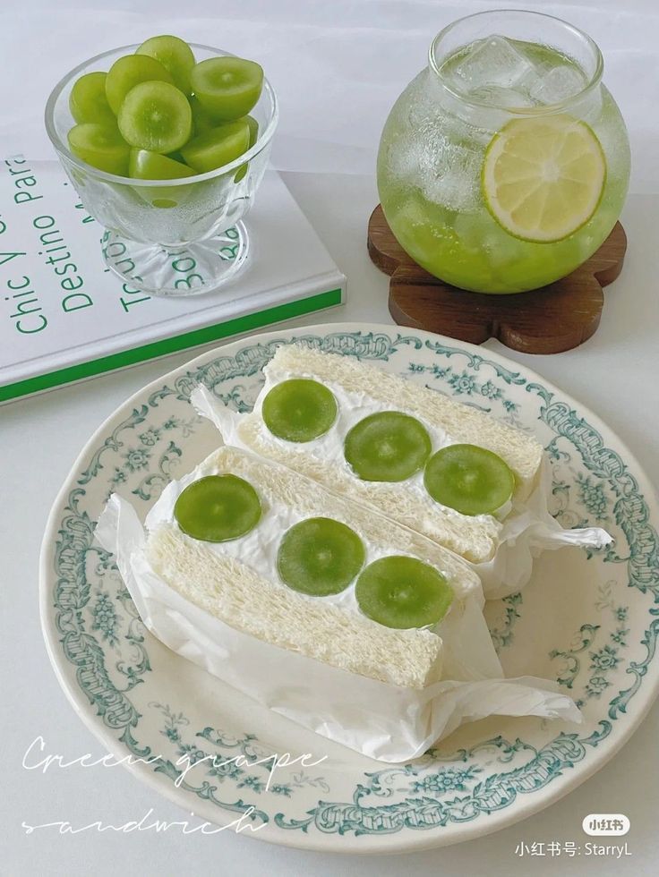 there is a piece of cake on a plate with grapes and limes in the bowl