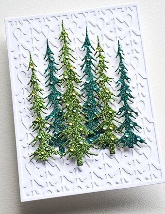 a card with three green christmas trees on the front and one in the back, sitting on a white surface