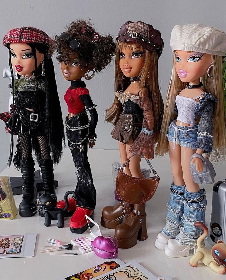 three dolls are standing next to each other on a table with various items around them