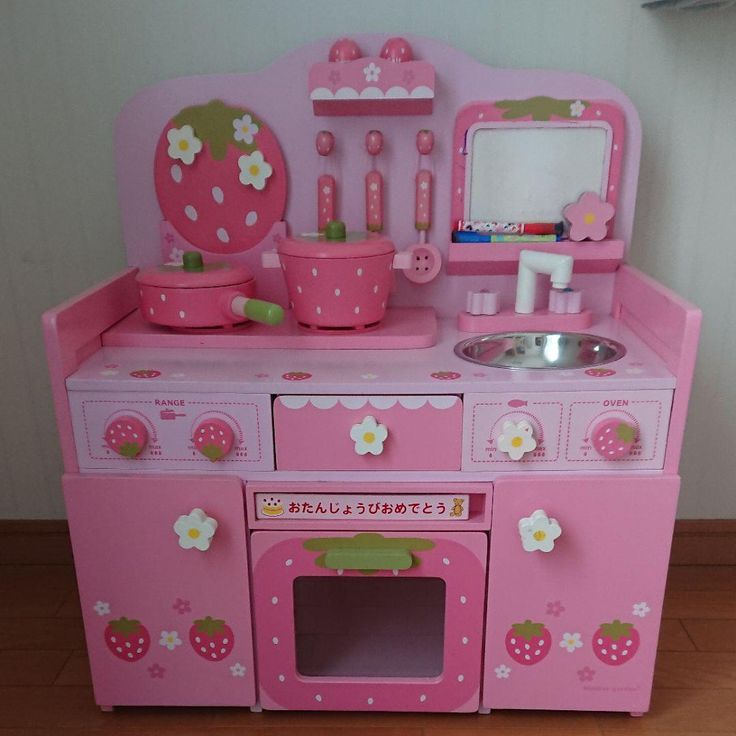 a pink wooden play kitchen with sink and stove