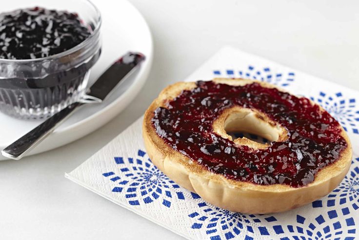 a jelly filled donut sitting on top of a napkin next to a bowl of jelly