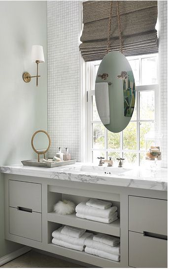 a bathroom with two sinks, mirrors and towels on the shelf in front of it