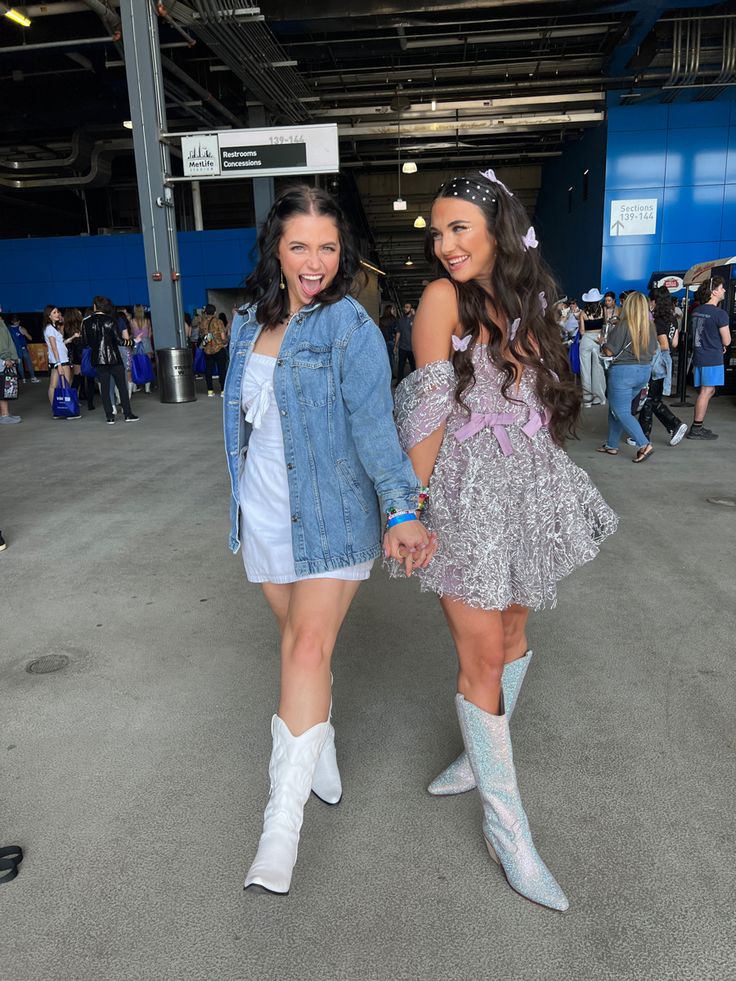 two women in cowboy boots holding hands and smiling at the camera while standing next to each other