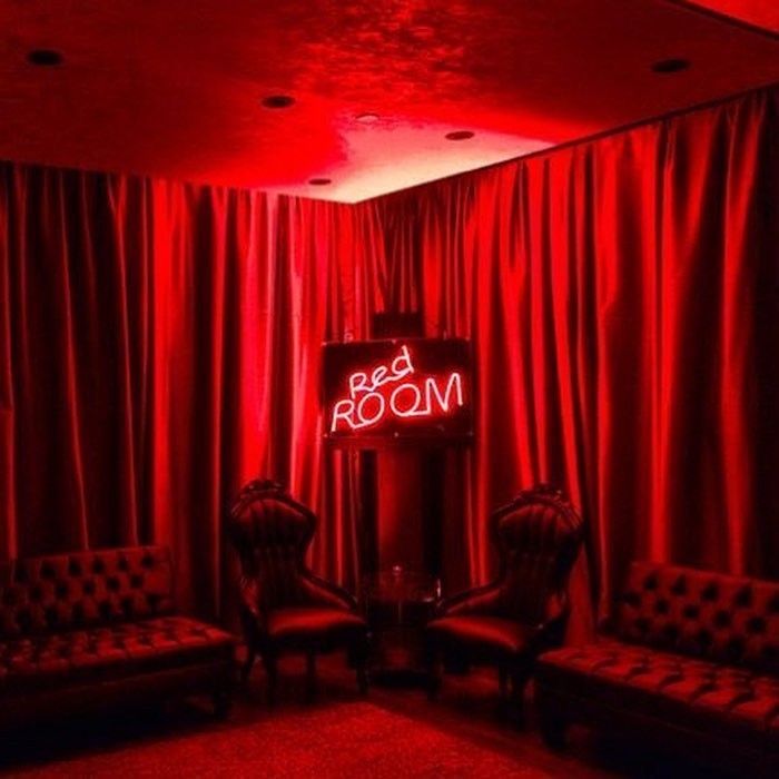 red room with two couches and a neon sign on the wall in front of it