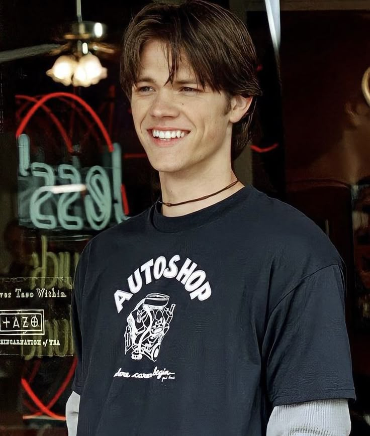 a young man standing in front of a store window