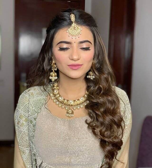 a woman with long hair wearing a necklace and earrings