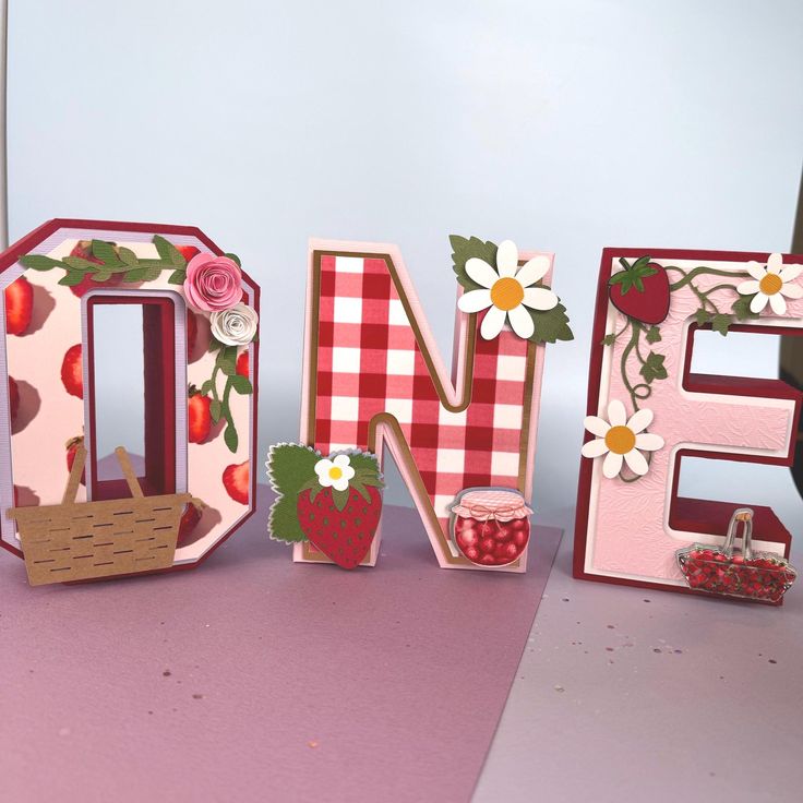 the letters are made out of wood and decorated with flowers, berries, and leaves