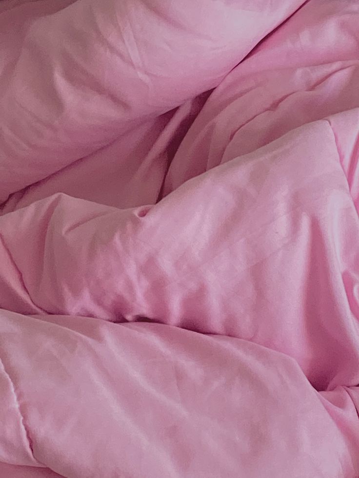 an unmade bed with pink sheets and pillows