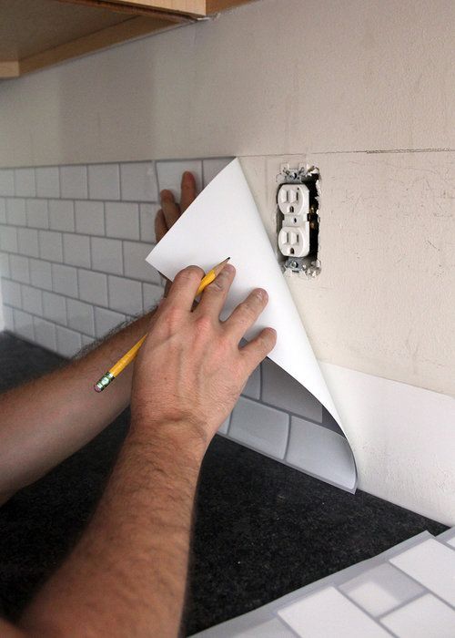 a man is using a pencil to draw something on the wall