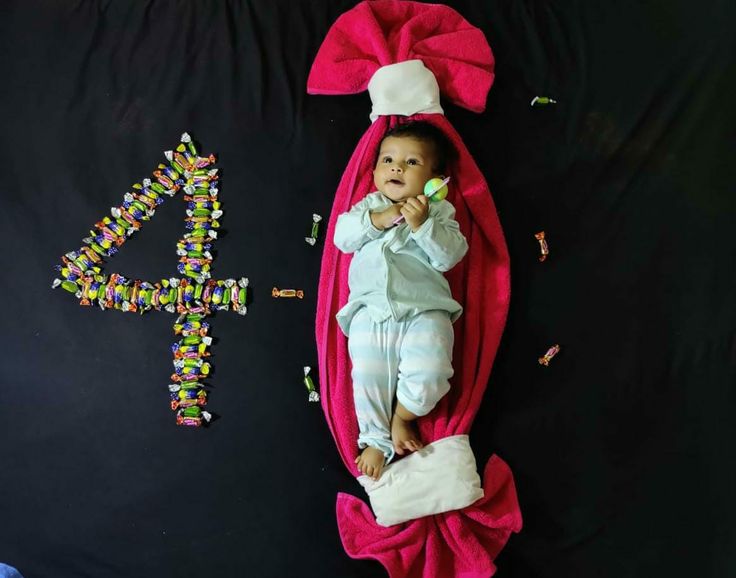 a baby laying on top of a pink blanket next to a number four sign with beads