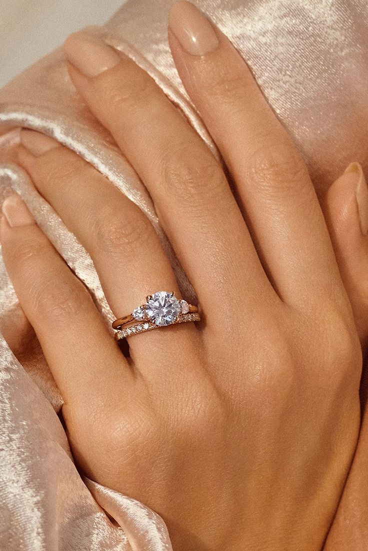 a woman's hand with a diamond ring on her finger, wrapped in satin material