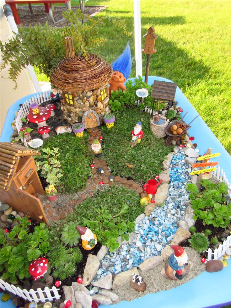 an outdoor garden with lots of plants and gnome figurines on the ground in it