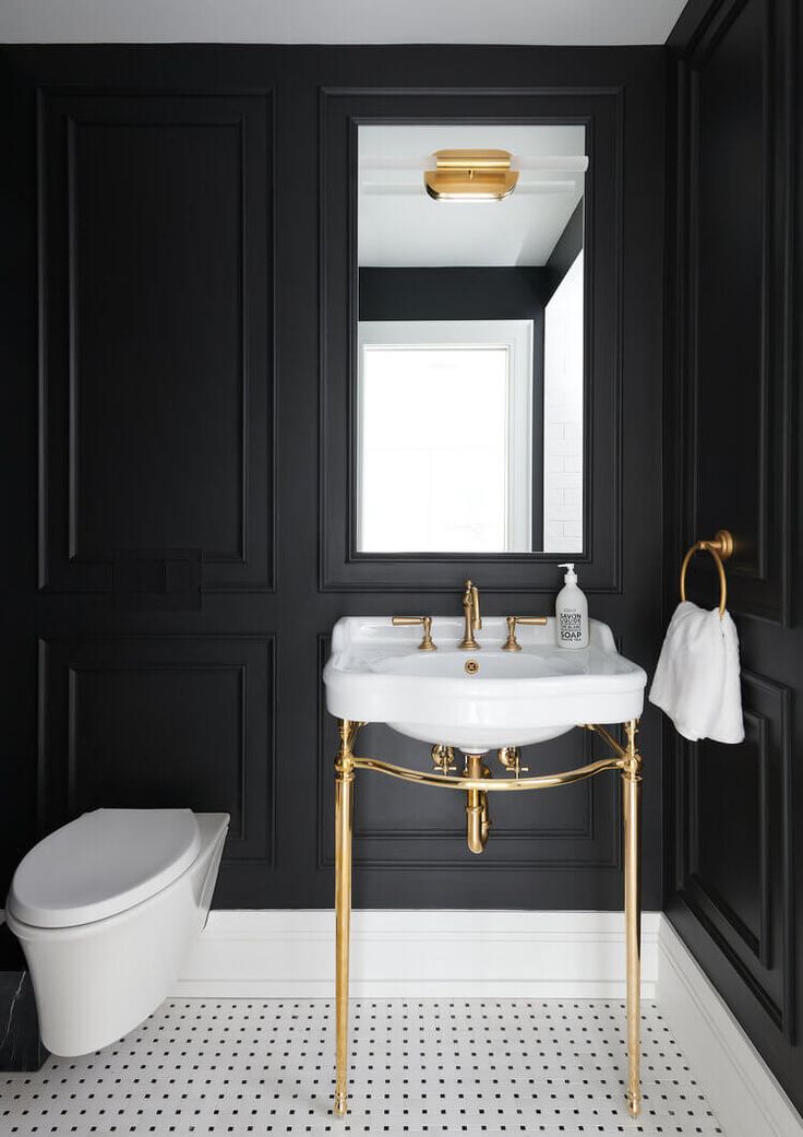 a black and white bathroom with gold fixtures, tile flooring and wall to wall paint