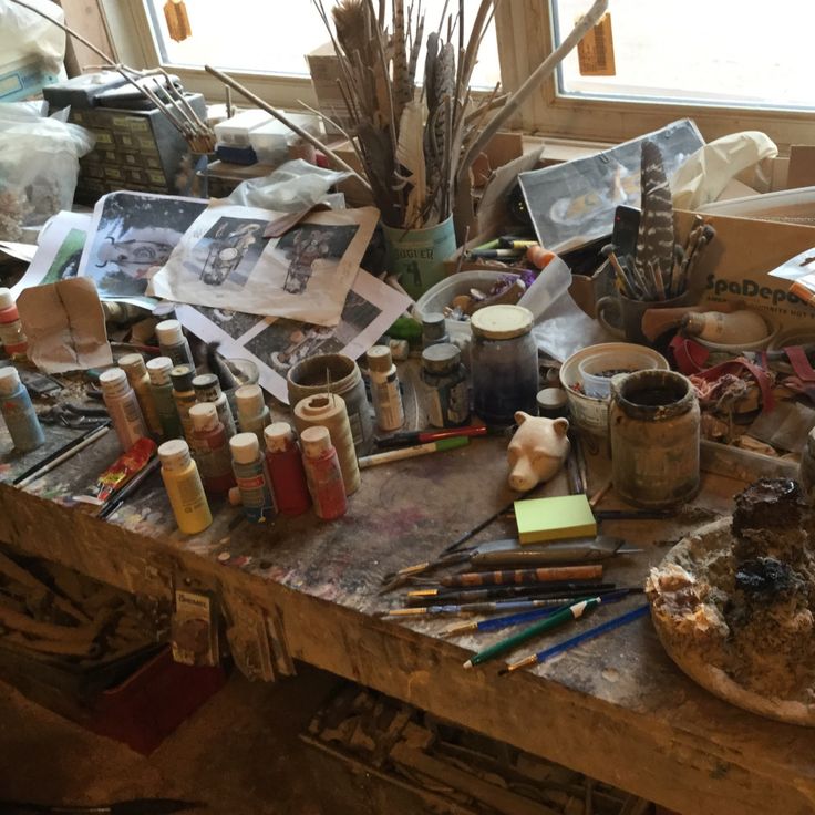 an artist's work table with lots of art supplies and paintbrushes on it