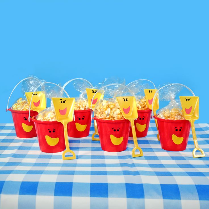 red buckets filled with popcorn sitting on top of a blue and white checkered table cloth