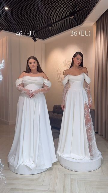 two women in white gowns standing next to each other with their hands on their hips