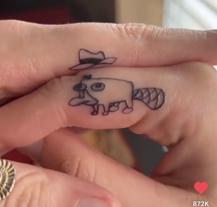 two people with tattoos on their fingers and one has a small cow in the middle