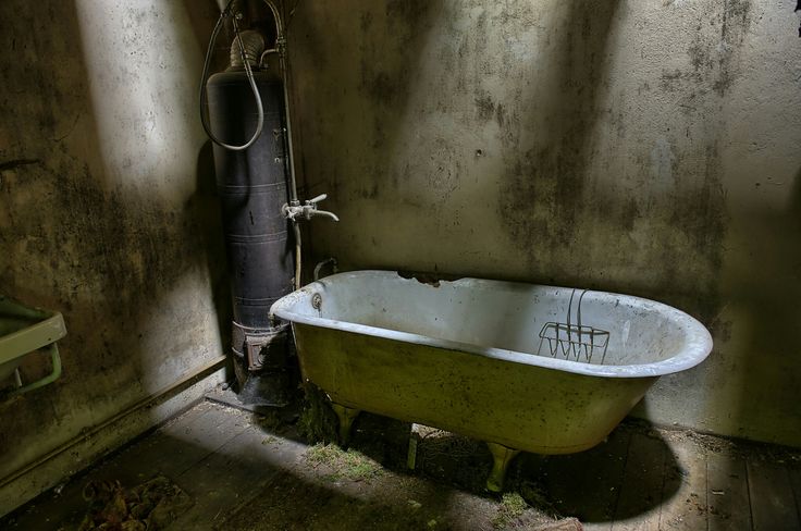 an old bathtub in the corner of a dirty bathroom