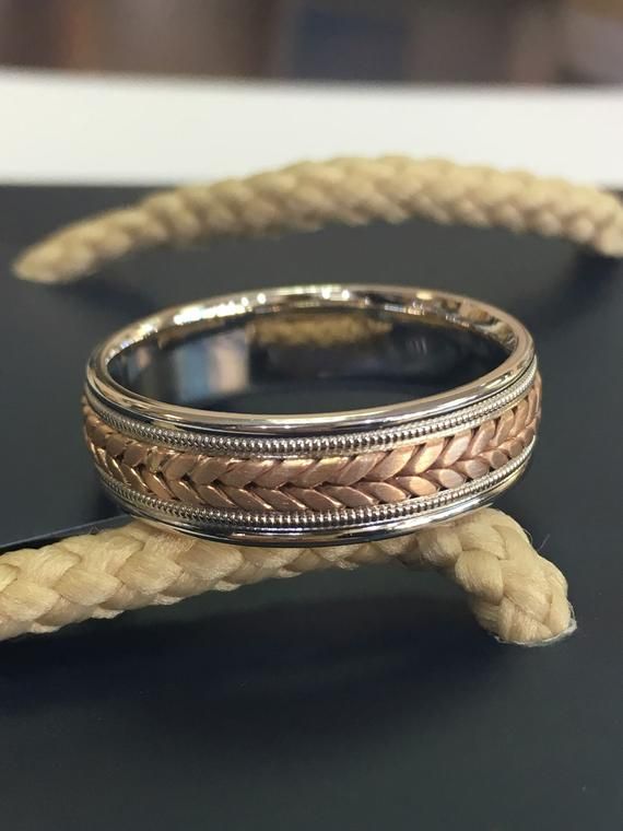 two silver rings sitting on top of a black table next to a white and brown rope