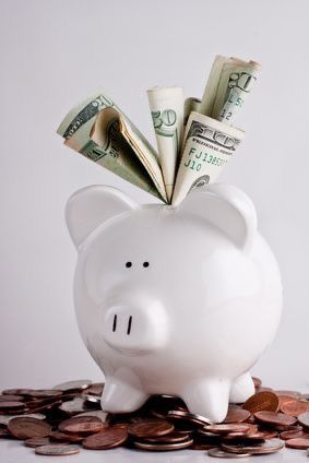 a white piggy bank with money sticking out of it's top on a pile of coins