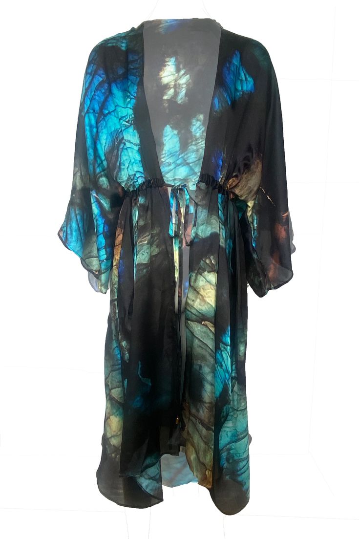 Schiller Silk Vivian Kimono print from MONA SWIMS TITAN Collection is a luxurious beach cover-up. Its patterned with a tribal inspired hand painted print, designed in-house at MONA SWIMS and created from light airy silk, featuring Kimono style sleeves and a ruched style drawstring belt feature with extra volume on the skirt, it can be worn open or closed. Wear it as evening wear or as luxury beachwear. 100% Silk Charmeuse Dry Clean Handmade in Ireland SCHILLER PRINT: an unusual iridescent or met Luxury Beachwear, Raffia Crochet, Goddess Gown, Athena Goddess, Kimono Style, Paint Print, Silk Charmeuse, Silk Kimono, Beach Covers