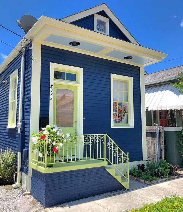 a small blue house with yellow trim and flowers in the window boxes on the front porch