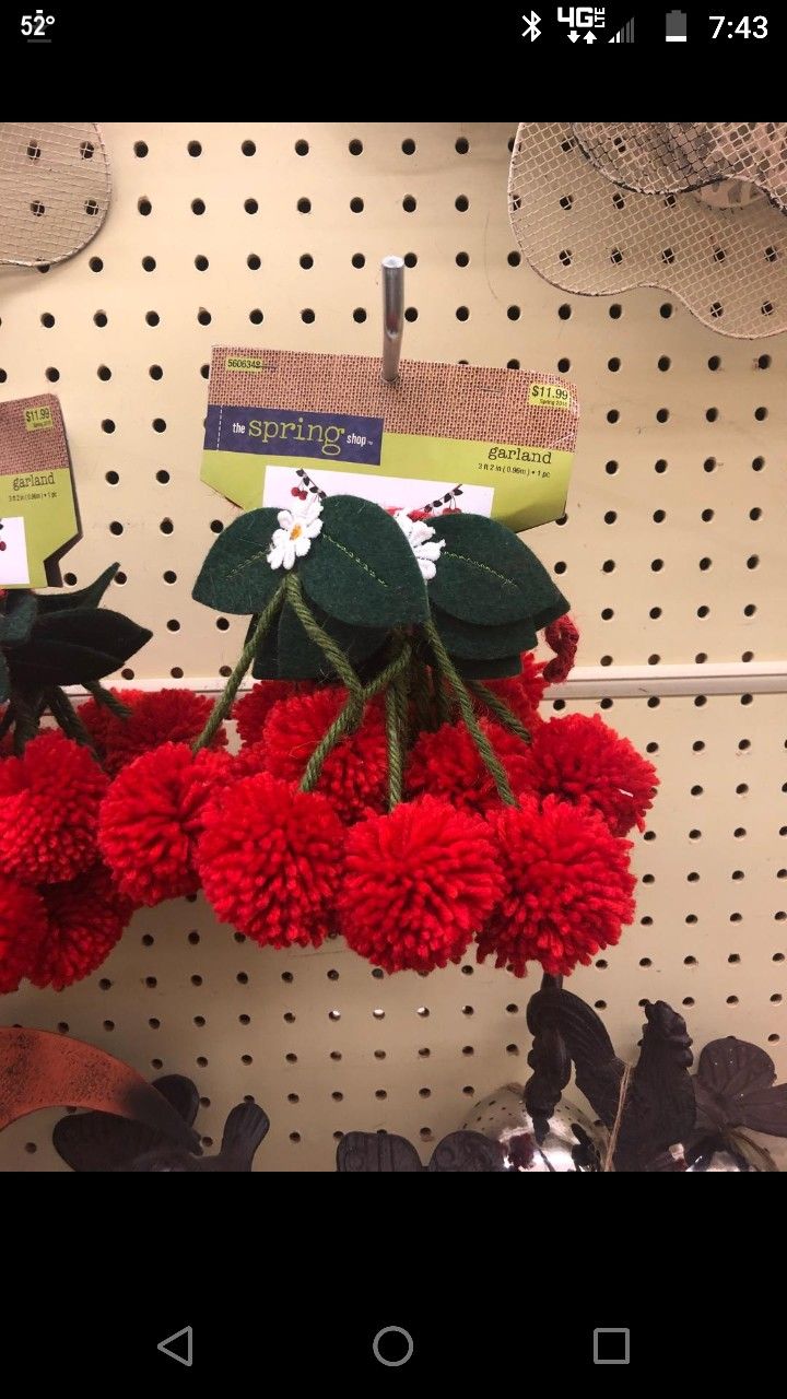 red pom - poms are hanging on the wall in a store with price tags