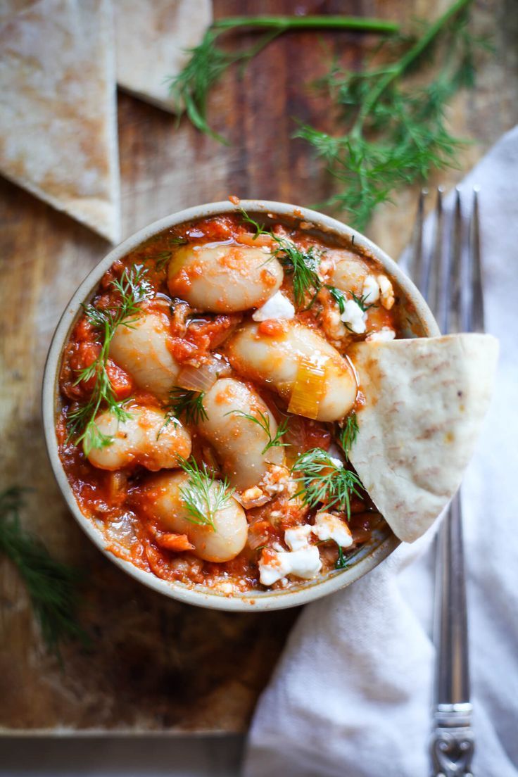 a bowl filled with shrimp and tomato sauce next to tortilla chips on a wooden table