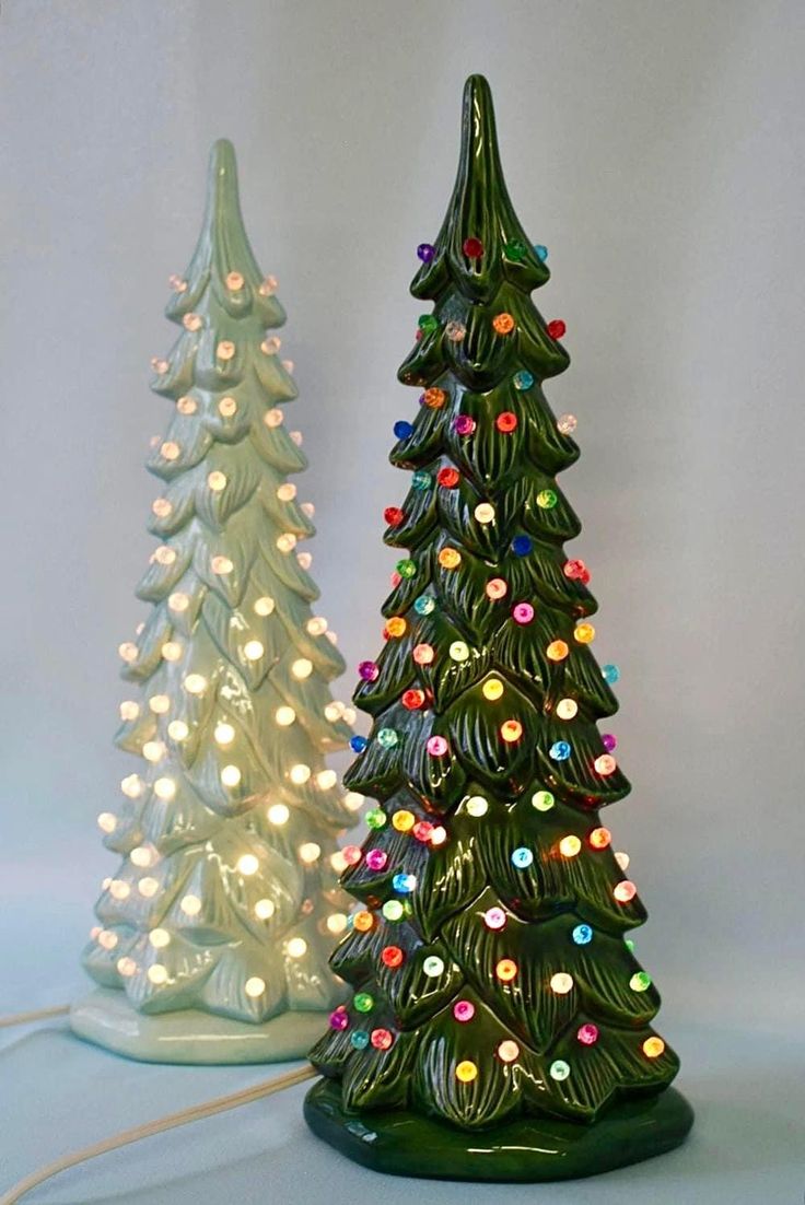 two ceramic christmas trees with lights on them