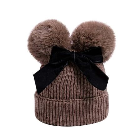 a brown hat with a black bow and two pom - poms on it