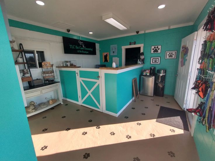 the inside of a small dog shop with blue walls and white counter tops, black paw prints on the floor