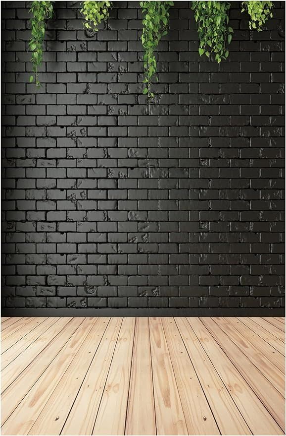 an empty wooden floor in front of a black brick wall with green plants hanging from it